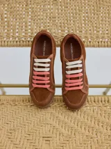 Championes marrones de cuero con cordones intercambiables blancos y rosas, y logo bordado en el lateral.