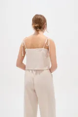 Musculosa de viscosa color natural, con breteles finos ajustables con lazos, cuello cuadrado y detalle bordado geométrico en el escote.