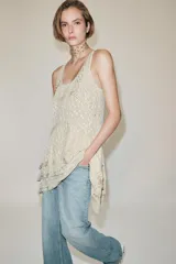 Vestido corto de viscosa color crudo, con escote redondo, manga sisa y diseño en jacquard con aplicaciones de abalorios. Presenta múltiples paneles superpuestos y bajo asimétrico.