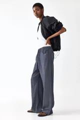 Pantalón recto de corte holgado con cintura elástica de tiro alto y cordón ajustable. Presenta bolsillos delanteros y traseros abiertos.
