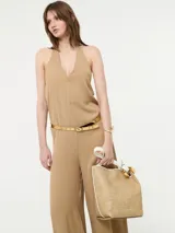 Mono color beige con escote halter, corte holgado, cinturón dorado y pantalones palazzo.
