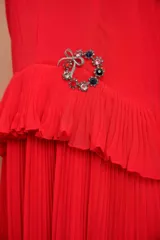 Broche plateado con forma de corona de adviento, adornado con gemas de colores y un lazo en la parte superior.