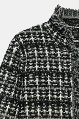 Chaqueta de punto con textura, manga larga y escote redondo. Presenta detalles de acabados deshilachados en los bordes y cierre frontal con ganchos.