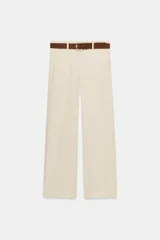 Pantalón culotte de tiro alto color beige, confeccionado con lino. Presenta pernera ancha y corta, bolsillos delanteros y falsos bolsillos de vivo en la espalda. Incluye un cinturón marrón con hebilla metálica redonda y cierre frontal con cremallera, botón interior y gancho.