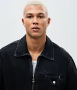 Chaqueta de jeans color negro con lavado desgastado, corte boxy, cuello camisero, cierre frontal con cremallera metálica y bolsillo frontal con cierre y solapa. Marca Blue Steel.