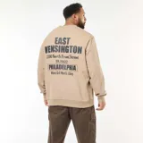 Buzo de cuello redondo en color beige, confeccionado en felpa ligera. Presenta un estampado gráfico en el pecho con la inscripción 'East Kensington Philadelphia' y puños y ruedo acanalados.