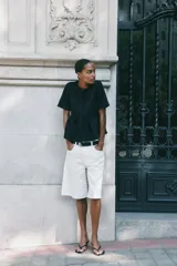 Top negro de manga corta con escote redondo y cierre frontal de botones forrados. Presenta un corte peplum con volado en la cintura.