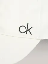 Gorra de béisbol blanca con visera curva y cierre ajustable trasero. Presenta el monograma "ck" bordado en hilo negro en el lateral.