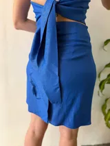 Conjunto de dos piezas color azul brillante, compuesto por un top halter con breteles finos y lazo regulable en el contorno, y una falda corta cruzada regulable.