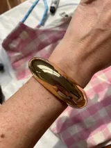 Brazalete rígido de diseño minimalista con acabado pulido brillante y forma redondeada.