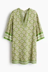 Vestido túnica corto de viscosa con estampado geométrico en tonos verdes y crudo, escote en V pronunciado tanto en el frente como en la espalda, mangas tres cuartos y diseño oversized.