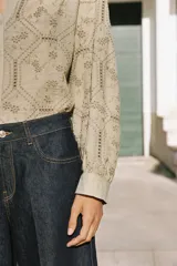 Camisa de cuello solapa con escote en V, manga larga y cierre frontal con botones. Presenta un diseño con bordados perforados en todo la prenda.