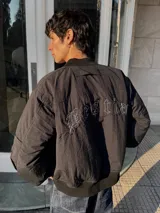 Campera bomber negra con cuello, puños y cintura acanalados. Presenta cierre frontal y bolsillos laterales. En la espalda tiene bordada la palabra "Bestia" en letras góticas blancas.