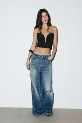Top strapless de color negro con escote corazón y cierre frontal con cremallera.