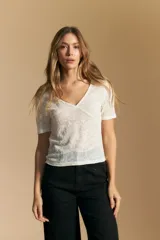 Top de manga corta confeccionado en tejido jacquard con textura en relieve. Presenta escote en V y un diseño frontal con líneas diagonales que crean un efecto cruzado.