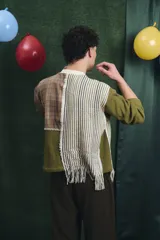 Buzo de manga larga con diseño patchwork que combina diferentes texturas y estampados, incluyendo tejido waffle verde oliva, tejido a rayas y cuadros en tonos grises y marrones, unidos con costuras visibles.