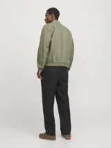 Campera bomber color verde claro, de tejido liviano de lino y algodón, con cuello tipo baseball, mangas largas con puños de canalé, cierre con cremallera y bolsillos delanteros.