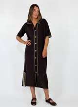 Vestido midi de punto color beige, con cuello solapa, mangas cortas y cierre frontal con botones. Presenta detalles de costuras y terminaciones en color mostaza, además de un diseño calado en el sector inferior de la falda.