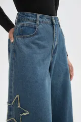 Pantalon de jean negro de corte ancho y tiro alto, con detalle de estrella bordada en la pierna y ruedo deshilachado.