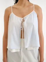 Blusa celeste claro con tirantes finos, escote en V y diseño abierto al frente con lazos para atar.
