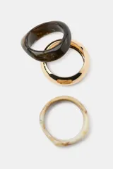 Pack de tres pulseras rígidas de diferentes formas y tamaños: una en tono marfil jaspeado, una dorada metálica brillante y otra oscura efecto carey.