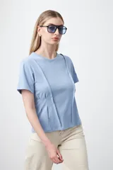 Remera de manga corta y cuello redondo, confeccionada en algodón. Presenta costuras verticales visibles en el frente que generan un efecto de entalle y estructura en la cintura.