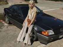 Pantalón de brocato color crudo con diseño floral en relieve, de tiro medio, corte acampanado con tajos laterales y cuatro bolsillos.