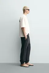Camiseta blanca de corte relajado, con cuello redondo, manga corta y texto estampado en contraste en el pecho.
