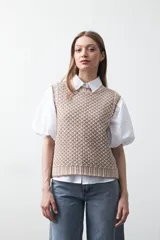 Chaleco tejido de algodón y acrílico, color rojo y blanco con patrón geométrico. Tiene cuello redondo y bordes acanalados en rojo.