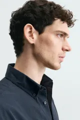 Camisa de corte regular fit confeccionada en tejido de algodón. Presenta cuello con solapa abotonada, cierre frontal con botones, manga larga con puños abotonados y un bolsillo plastrón en el pecho.