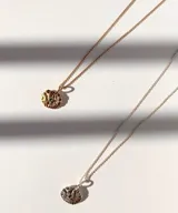 Collar con cadena dorada y dije redondo con la figura del Espíritu Santo y una pequeña piedra verde.