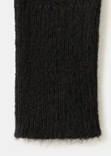 Cardigan negro de punto con escote en V cruzado, volados decorativos en los bordes y mangas largas con puños extendidos.
