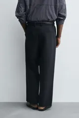 Pantalón de corte relajado en color verde militar, con diseño de pliegues frontales, bolsillos laterales y cierre de cremallera con botón.