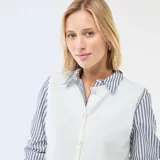 Chaleco de punto color beige crudo, con escote en V, cierre frontal con botones y diseño sin mangas.