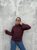 Polera de punto color bordó, con cuello alto abierto lateralmente, mangas largas amplias y corte recto.