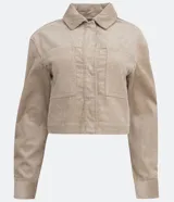 Campera corta color beige de pana con cuello camisero, cierre frontal con botones, bolsillos de parche en el pecho y mangas largas con puños abotonados.