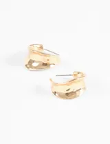 Par de aros tipo argolla gruesa, dorados, con forma curva y textura martillada o pulida irregular.