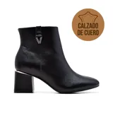 Bota corta de cuero negro con punta fina, cierre lateral y detalle de hebilla con strass. El taco es ancho con detalle metálico plateado.