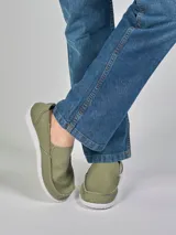 Mocasines de lona color verde oliva con elástico en los laterales y suela blanca.