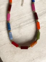 Collar corto tipo gargantilla compuesto por cuentas cilíndricas de colores variados intercaladas con pequeñas esferas doradas.