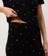 Pijama largo negro de viscolycra con estampa floral, compuesto por una remera de manga corta con escote en V y aplicación de encaje, y un pantalón con cintura elastizada.