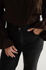 Pantalón cropped de tiro medio con acabado engomado, corte recto y bolsillos laterales. Presenta cierre frontal con botón y costuras a tono.