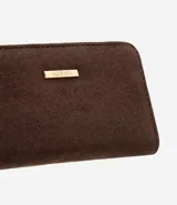 Billetera pequeña Satinato con textura tipo gamuza, cierre metálico superior y correa de mano lateral. Cuenta con placa metálica decorativa en el frente y divisiones internas para organización.
