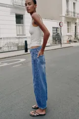 Jeans de tiro medio con cinco bolsillos, pernera holgada y diseño barrel, con costuras decorativas frontales y cierre de cremallera y botón.