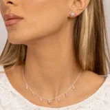 Collar plateado con cadena de eslabones y dijes colgantes: estrellas con topacios blancos, piedras redondas de topacio azul y una piedra ovalada de topacio azul en el centro.