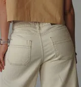 Pantalón de jean color natural, de corte ancho con costuras a la vista y terminación desflecada.