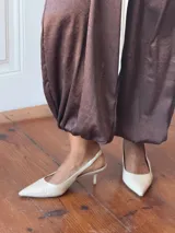 Pantalón de corte holgado y tiro alto, confeccionado en tela satinada color marrón oscuro. Presenta cintura elástica con cordón ajustable y diseño amplio en las piernas.