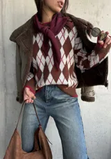 Sweater de tejido de punto con diseño de rombos en tonos chocolate, blanco y detalles en bordó. Presenta cuello redondo, mangas largas y terminaciones acanaladas en puños y ruedo.