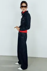 Jeans de tiro alto confeccionados en denim azul oscuro, con diseño barrel de pernera holgada que se estrecha hacia los tobillos. Cuenta con cinco bolsillos, trabillas para cinto y cierre frontal con cremallera y botón.