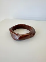 Pulsera rígida de acrílico con diseño asimétrico y acabado marmolado en tonos marrones y blancos.